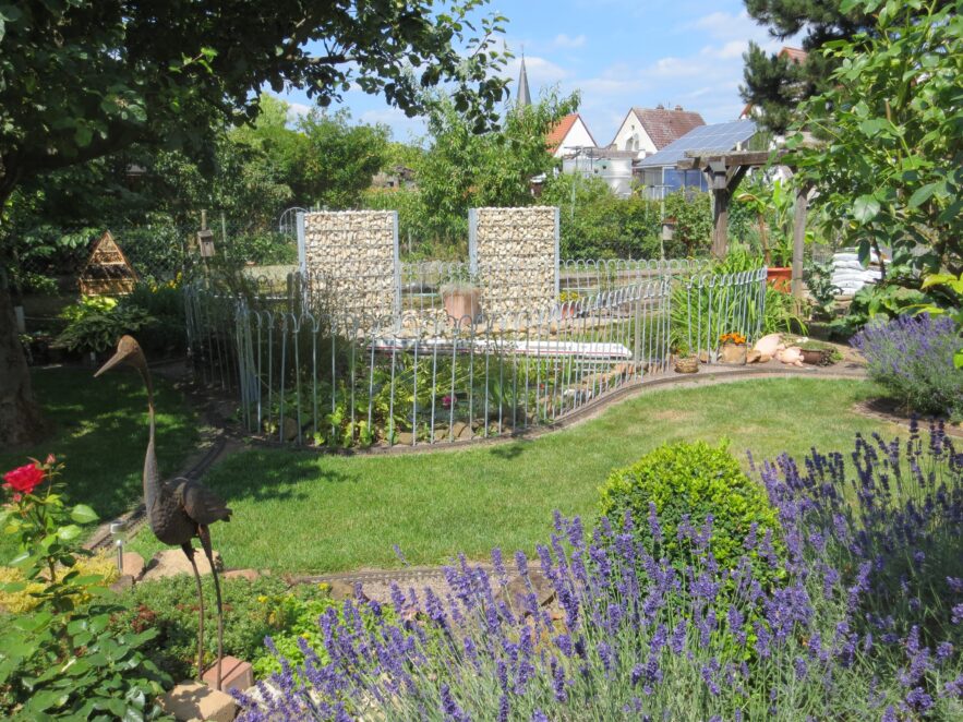 Eingezäunter Gartenteich mit Modelleisenbahn