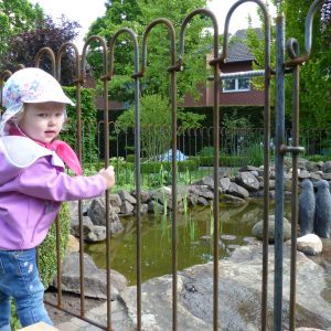 L'enfant est protégée de l'étang par la clôture métallique