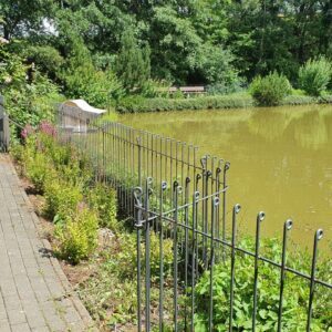 Urbaner Zaun in einer Parkanlage von einem Seniorenheim um einen Teich zur Sicherheit