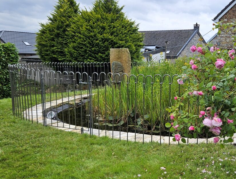 Clôture d'étang light-125-brut avec porte comme passage devant un étang de jardin.