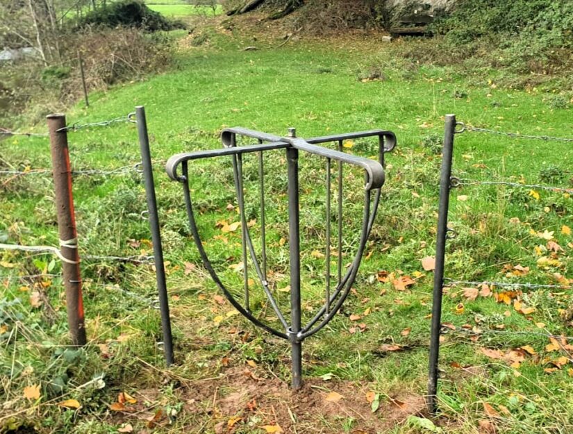 Een wandelpoort die in de omheining tussen twee weilanden in de riviervallei is ingebouwd.