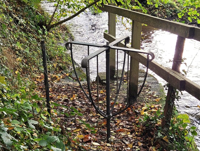 Een wandelpoort tussen weiland, beek en bos, zodat het vee er niet doorheen kan.