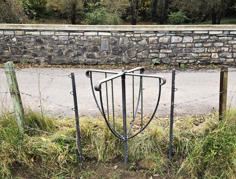 L'accès à un sentier de randonnée dans une prairie depuis la route se fait par un tourniquet.
