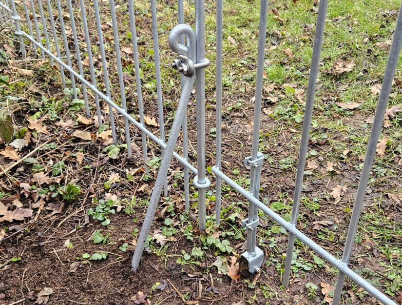 Die Abstützstrebe wird im Abstand von 20 cm zum Zaun in den Boden eingeschlagen.