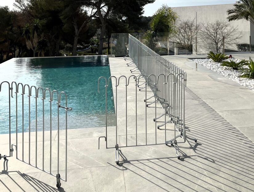 Clôture de piscine galvanisée avec portail ouvert et pieds actuels.