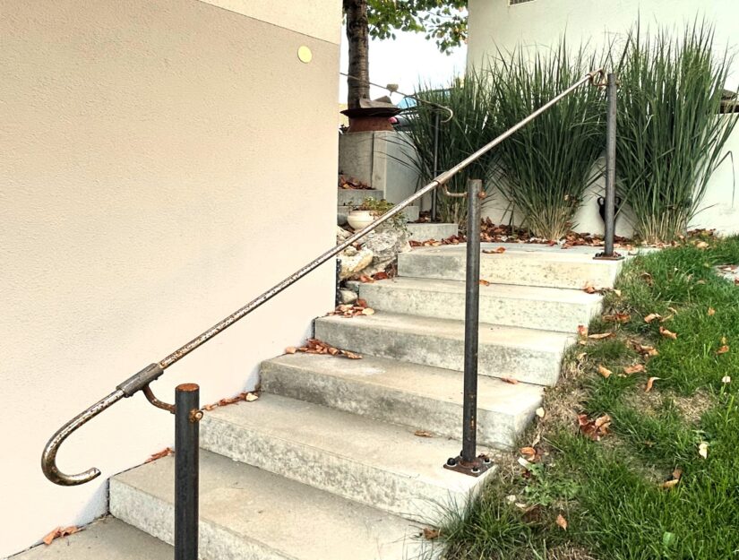 Der Handlauf aus Eisen mit Rostpatina ist sicher auf der Betontreppe aufgedübelt.
