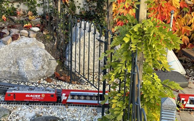 Modelleisenbahn um Gartenteich mit Zaun