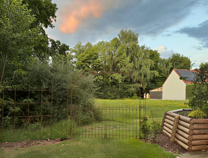 Une arche de roses avec un double portail à côté d'un treillis Melabel®.