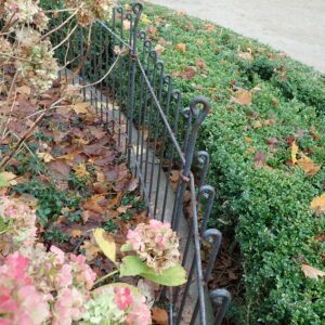 Zaun um ein Blumenbeet im Stadtpark, welches Hunde und Personen aus den Beeten fernhalten soll