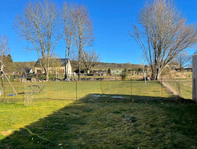 115 cm hoher Zaun aus rostigem Eisen teilt den Rasen in zwei Teile ab.