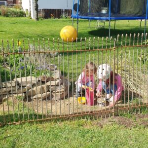 Die Kinder vom Nachbarn spielen hinter dem rostenden Zaun