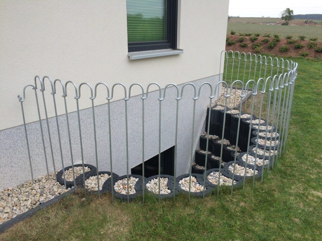 Mobiel steekhek dat een lichtschacht en keldertrap in de tuin veilig omheint als valbeveiliging voor kinderen en honden