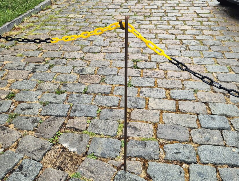 De kettingpaal is in een voeg tussen de straatstenen gestoken.