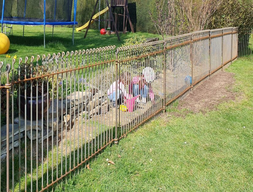 Die Kinder vom Nachbarn spielen hinter dem rostenden Zaun.