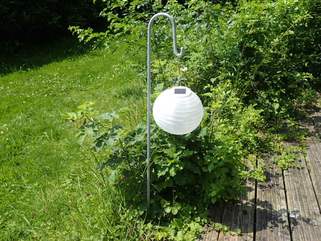 Der gebogene Lanternenstab hält eine Solarlampe.