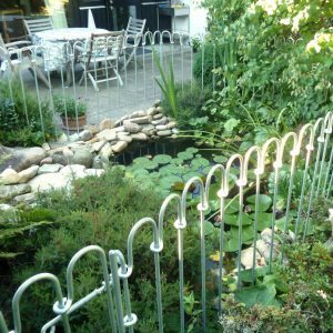 Geschmiedete Stäbe bilden einen stabilen Zaun vor dem Teich als Kinderschutz