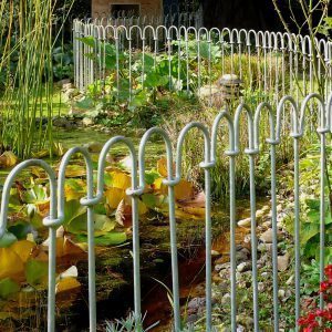 Verzinkter Zaun um einen Gartenteich mit Seerosen