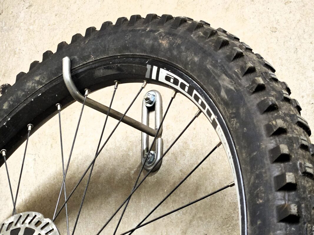 Een e-bike van 25 kg hangt met het voorwiel aan de haak. Grote wandhaak Roestvrijstalen wandhaken