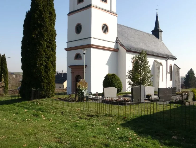 In de grond gestoken hek van een begraafplaats voor een kerk in de Eifel.